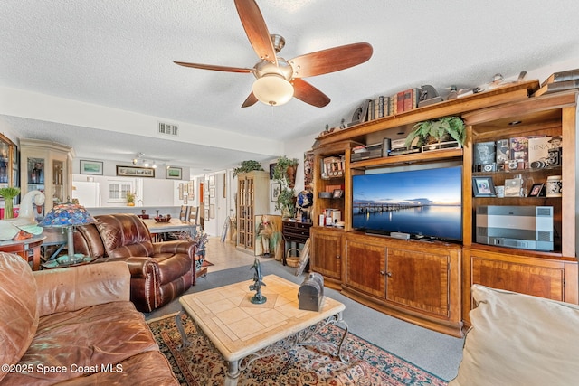 living area with a ceiling fan and a textured ceiling