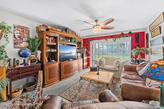 living area featuring ceiling fan, carpet floors, and a textured ceiling