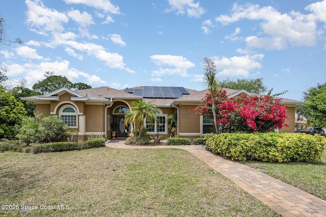 view of front facade featuring a front yard, stucco siding, and roof mounted solar panels