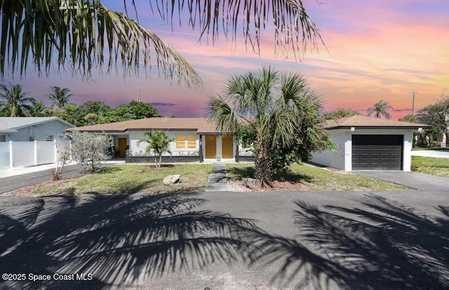 single story home with driveway, fence, a garage, and stucco siding