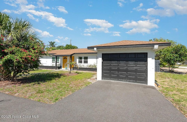 ranch-style home with a front lawn, asphalt driveway, and stucco siding