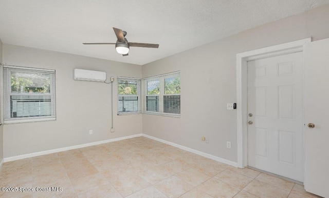 spare room featuring an AC wall unit, ceiling fan, and baseboards