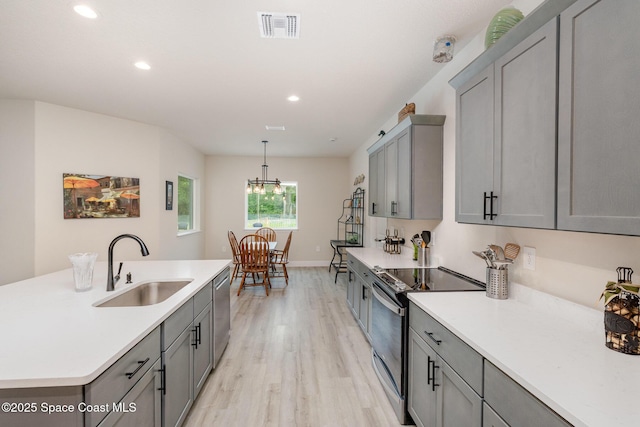 2602 Flintstone Ave SE, Palm Bay, FL 32909 - kitchen with stainless steel appliances, gray cabinetry, a sink, light wood-type flooring, and light countertops