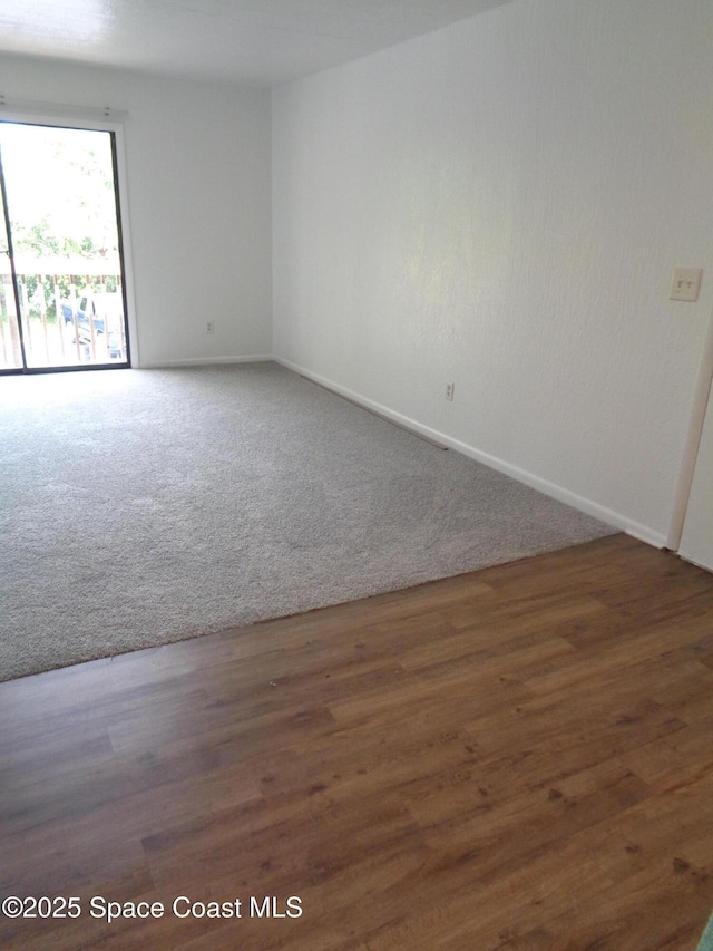 carpeted spare room with baseboards and wood finished floors