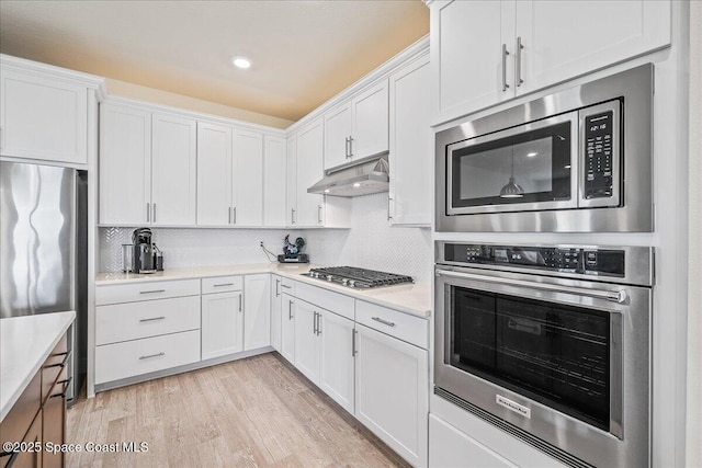2902 Tidepool Pl, Melbourne, FL 32940 - kitchen with appliances with stainless steel finishes, under cabinet range hood, white cabinetry, light countertops, and recessed lighting