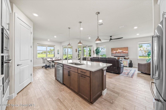 2902 Tidepool Pl, Melbourne, FL 32940 - kitchen with a sink, stainless steel appliances, open floor plan, light wood-style flooring, and a kitchen island with sink