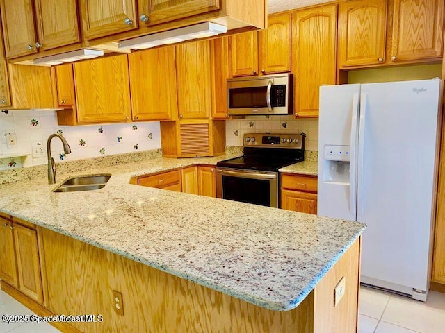 kitchen with stainless steel appliances, a sink, light stone counters, and tasteful backsplash