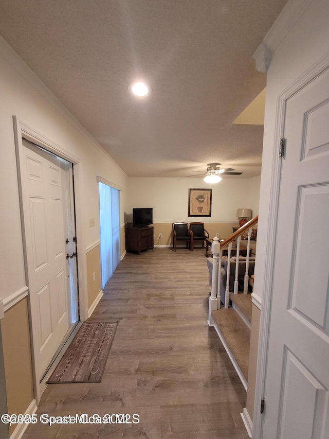 corridor with crown molding, stairway, wood finished floors, recessed lighting, and baseboards