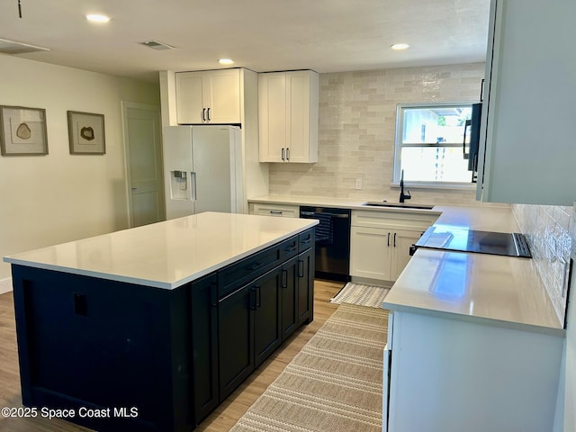 kitchen with black dishwasher, white fridge with ice dispenser, a sink, stovetop, and light wood-type flooring