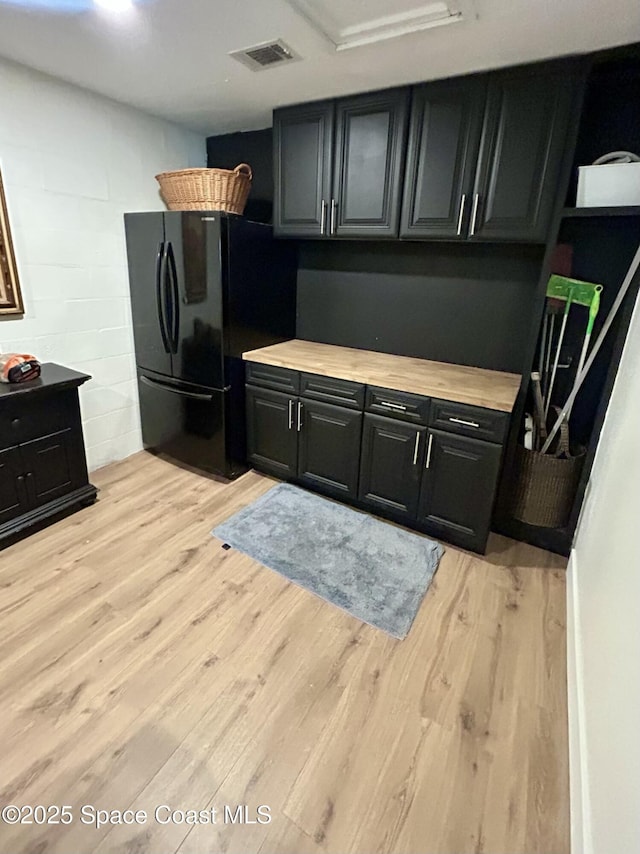 kitchen with freestanding refrigerator, light wood-style floors, light countertops, and concrete block wall