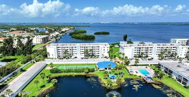 bird's eye view of apartment complex, a nearby body of water, and a pool area