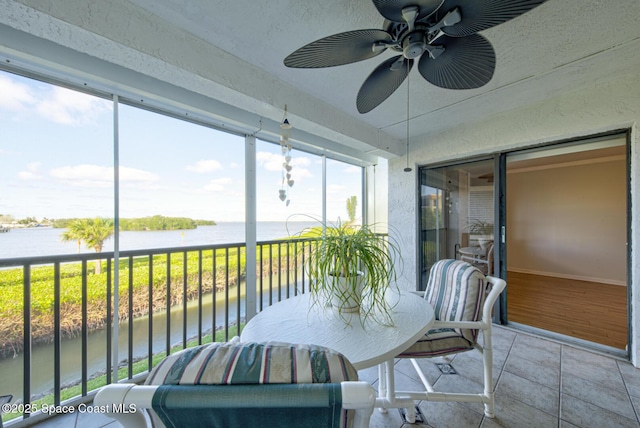 sunroom with a water view, ceiling fan, and healthy amount of natural light