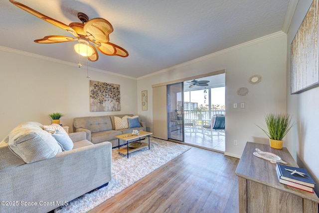 living area with wood finished floors, a ceiling fan, ornamental molding, and baseboards