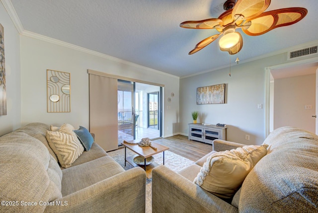 living room with light wood-style floors, crown molding, ceiling fan, and baseboards