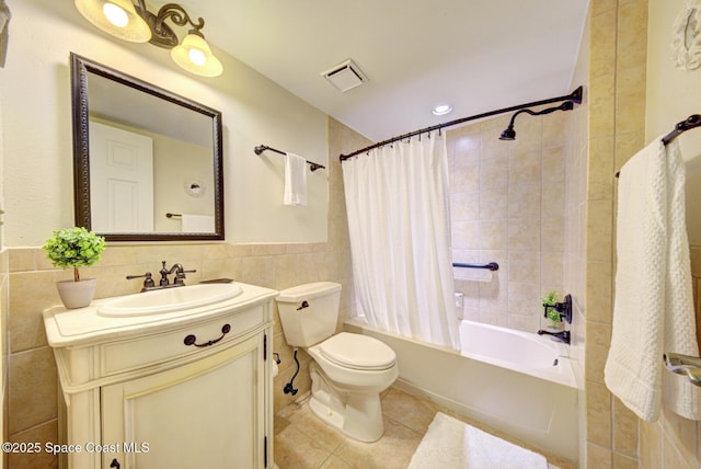 full bathroom featuring tile walls, tile patterned flooring, toilet, vanity, and shower / bath combo with shower curtain