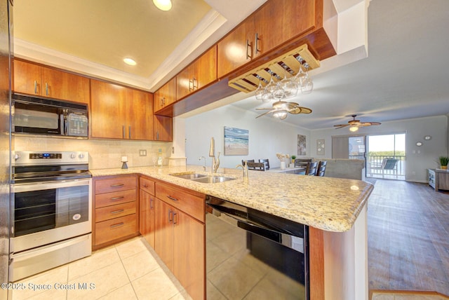 kitchen with black appliances, a sink, a peninsula, a ceiling fan, and brown cabinets