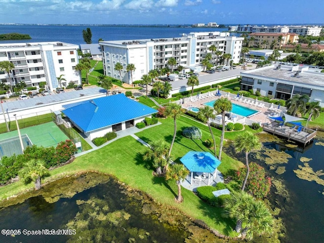 drone / aerial view of a pool area, apartment complex, and a large body of water