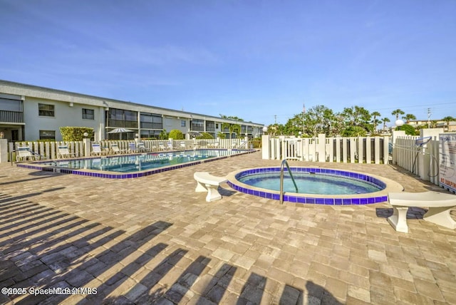 community pool featuring a community hot tub, fence, and a patio area