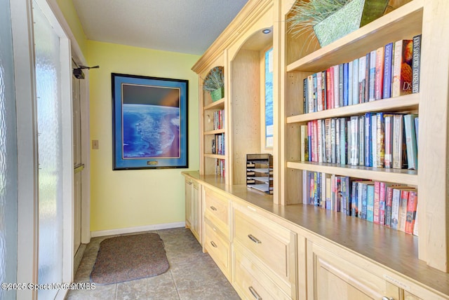 hall with baseboards, tile patterned floors, and a textured ceiling