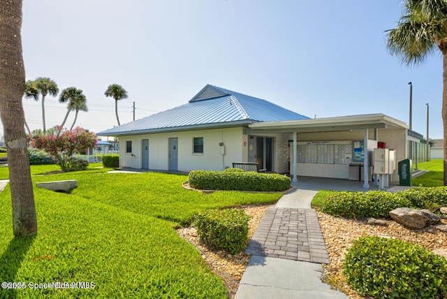 view of front facade with metal roof, a front lawn, and stucco siding