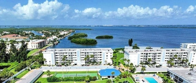 bird's eye view of apartment complex, a nearby body of water, and a pool area
