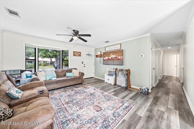 living room with crown molding, wood finished floors, a ceiling fan, baseboards, and a textured ceiling