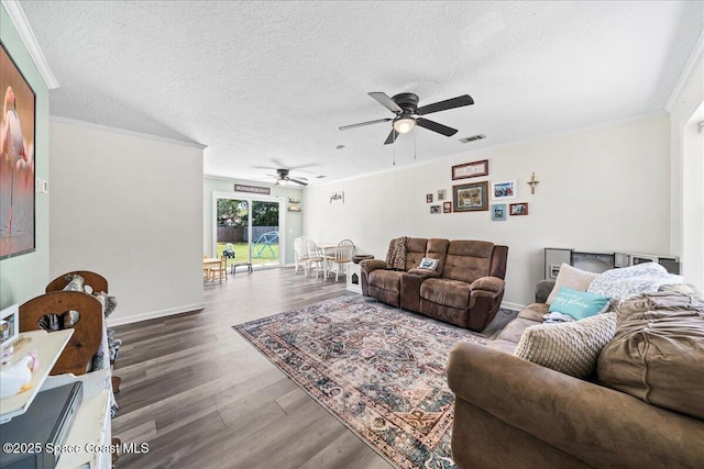 living area with wood finished floors, ceiling fan, a textured ceiling, crown molding, and baseboards