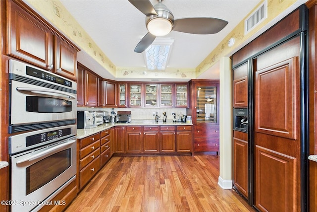 732 Bayside Dr Unit 501, Cape Canaveral, FL 32920 - kitchen with double oven, light wood-style flooring, a ceiling fan, glass insert cabinets, and paneled built in refrigerator