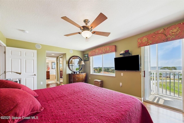 732 Bayside Dr Unit 501, Cape Canaveral, FL 32920 - bedroom with access to exterior, wood finished floors, connected bathroom, a textured ceiling, and baseboards