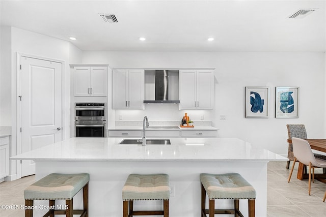 1342 Great Belt Cir, Melbourne, FL 32940 - kitchen with wall chimney range hood, a sink, stainless steel double oven, a breakfast bar area, and recessed lighting