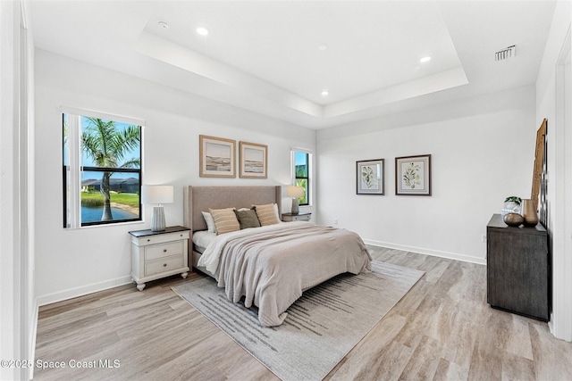 1342 Great Belt Cir, Melbourne, FL 32940 - bedroom featuring a tray ceiling, multiple windows, light wood finished floors, and recessed lighting