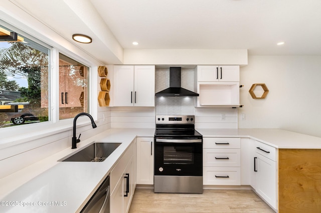 kitchen with wall chimney exhaust hood, stainless steel appliances, a sink, white cabinets, and recessed lighting