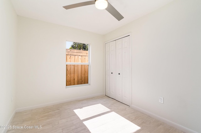 unfurnished bedroom featuring a closet, wood finished floors, baseboards, and a ceiling fan