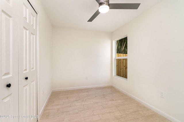 empty room with ceiling fan, light wood-style floors, and baseboards