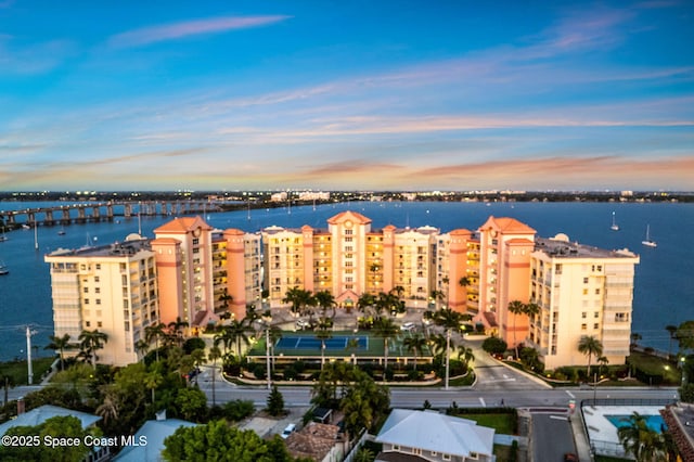aerial view at dusk of a water view, a view of apartment building / complex, and a notable bridge
