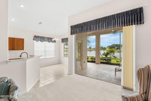 4882 Worthington Cir, Rockledge, FL 32955 - kitchen with brown cabinetry, a water view, plenty of natural light, vaulted ceiling, and light tile patterned floors