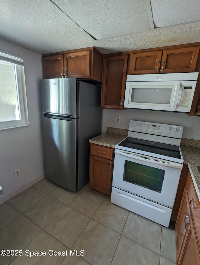 1600 University Ln Unit 1504, Cocoa, FL 32922 - kitchen featuring white appliances, light tile patterned flooring, brown cabinets, and a textured ceiling