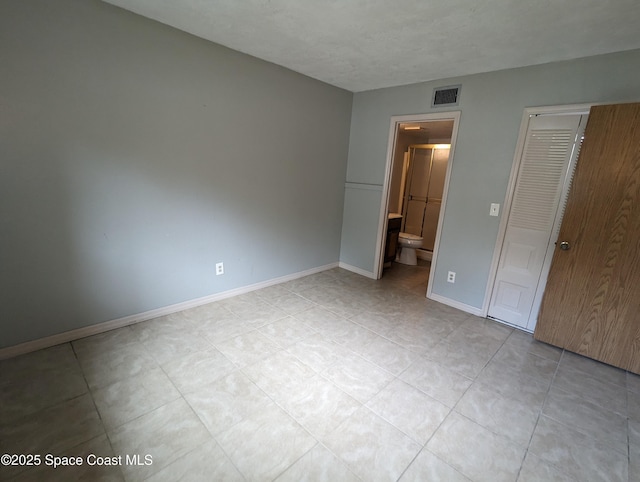 1600 University Ln Unit 1504, Cocoa, FL 32922 - unfurnished bedroom with baseboards, light tile patterned flooring, and ensuite bath