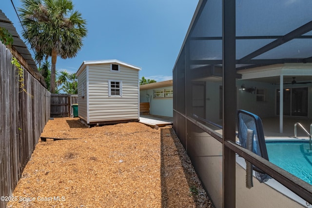fenced backyard featuring an outbuilding, a storage unit, glass enclosure, a patio area, and ceiling fan