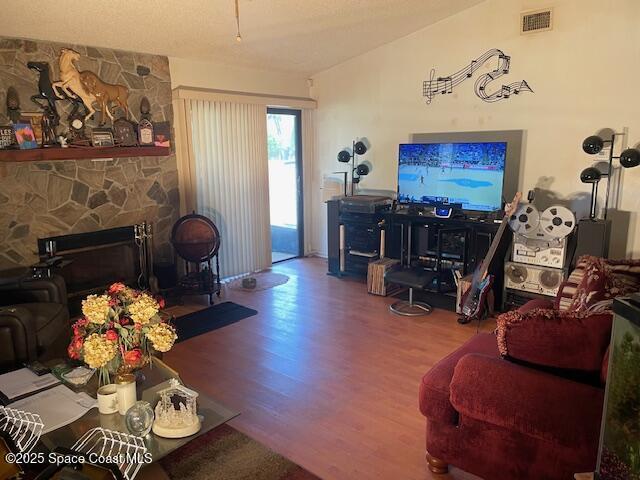 living room with wood finished floors and a stone fireplace