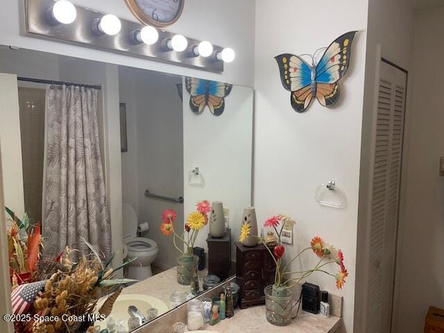 bathroom with toilet, curtained shower, a closet, and vanity