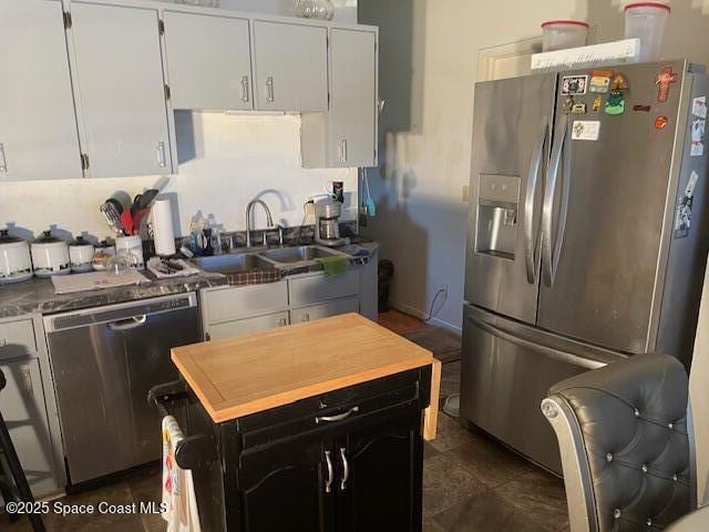 kitchen featuring stainless steel appliances, a sink, white cabinetry, and dark cabinetry
