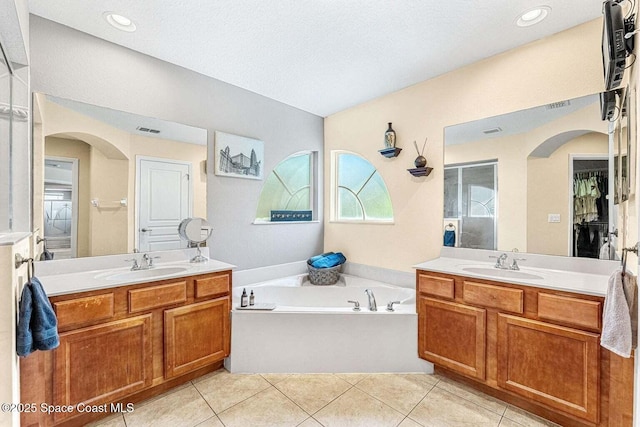 bathroom featuring two vanities, a garden tub, and tile patterned floors