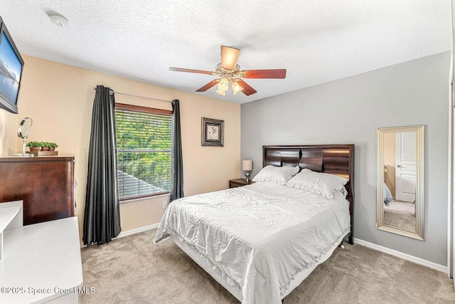 bedroom with light carpet, baseboards, ceiling fan, and a textured ceiling