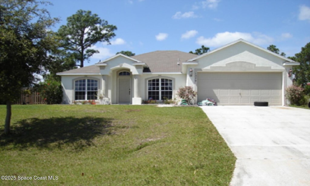 single story home featuring an attached garage, a front yard, driveway, and stucco siding