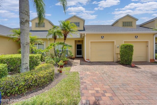 view of front of home with a garage, stucco siding, and decorative driveway