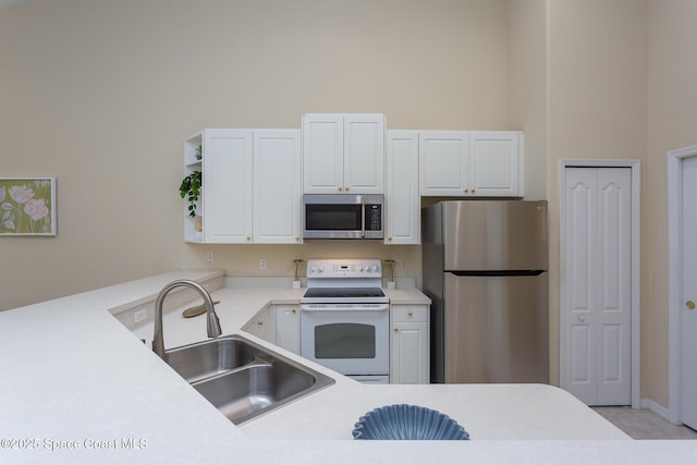 kitchen featuring stainless steel appliances, a sink, light countertops, white cabinets, and a high ceiling