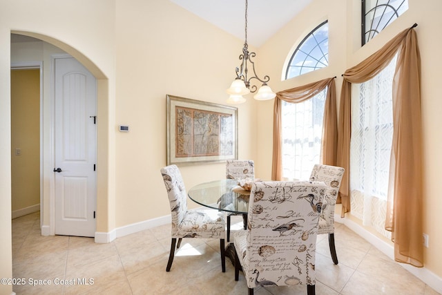 679 Sheridan Woods Dr, Melbourne, FL 32904 - dining space featuring arched walkways, light tile patterned floors, a chandelier, lofted ceiling, and baseboards