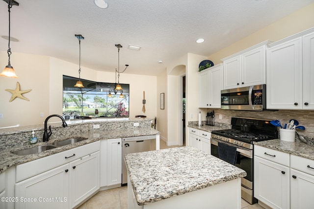 679 Sheridan Woods Dr, Melbourne, FL 32904 - kitchen featuring appliances with stainless steel finishes, a sink, arched walkways, decorative backsplash, and white cabinetry
