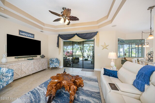 679 Sheridan Woods Dr, Melbourne, FL 32904 - living room with tile patterned flooring, a ceiling fan, a tray ceiling, and plenty of natural light